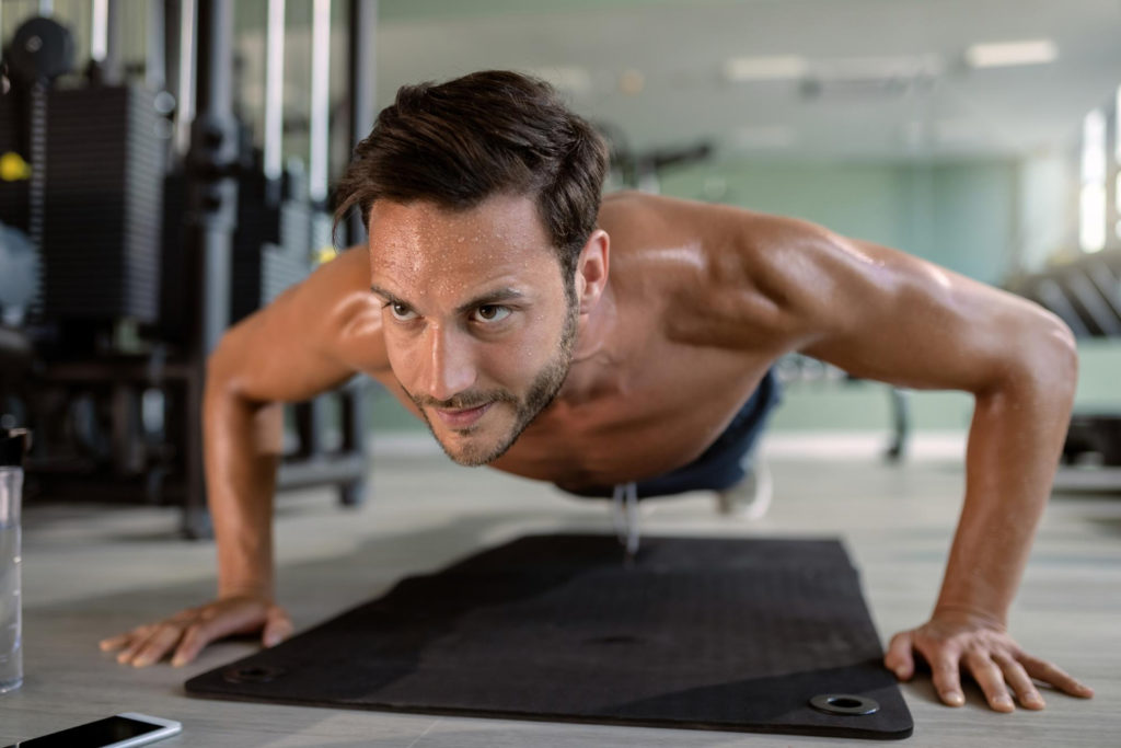 young-athletic-man-doing-pushups-during-sports-training-gym