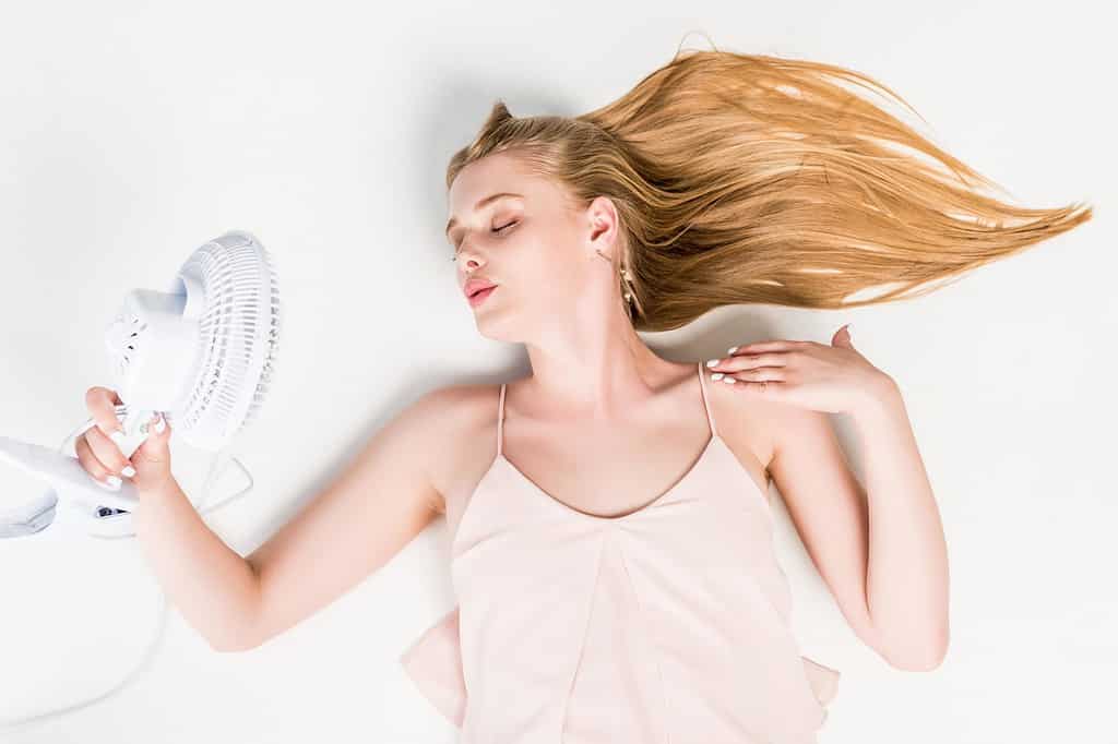 Blonde girl cooling down with a fan