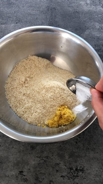Add salt and lemon zest to ground almonds