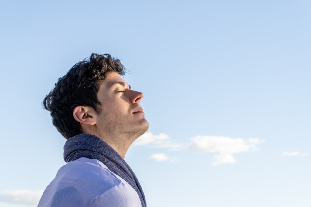 Man breathing with clouds in the background